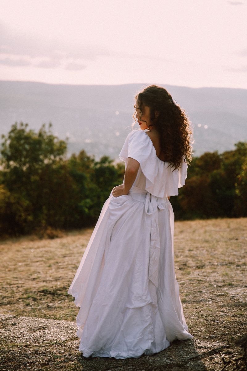 A woman in a white dress turning away, looking back over her shoulder