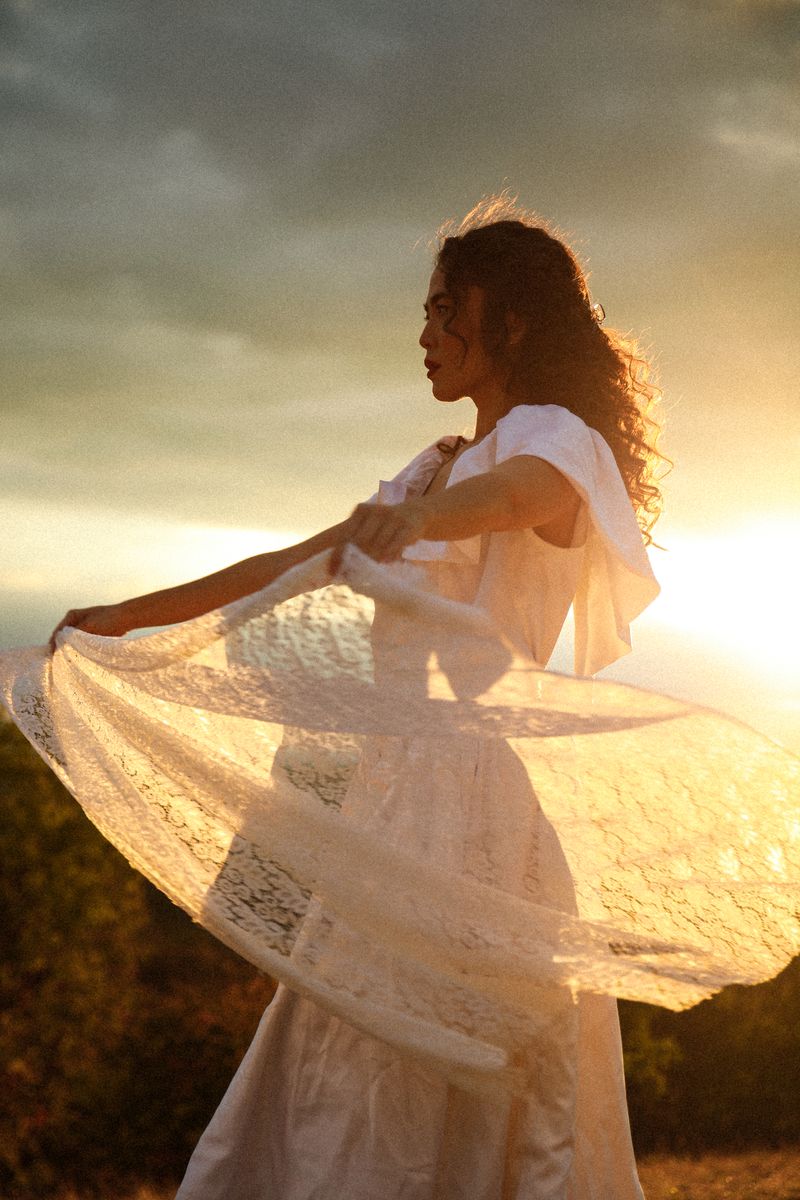 A woman spreading a lace skirt against the sunset