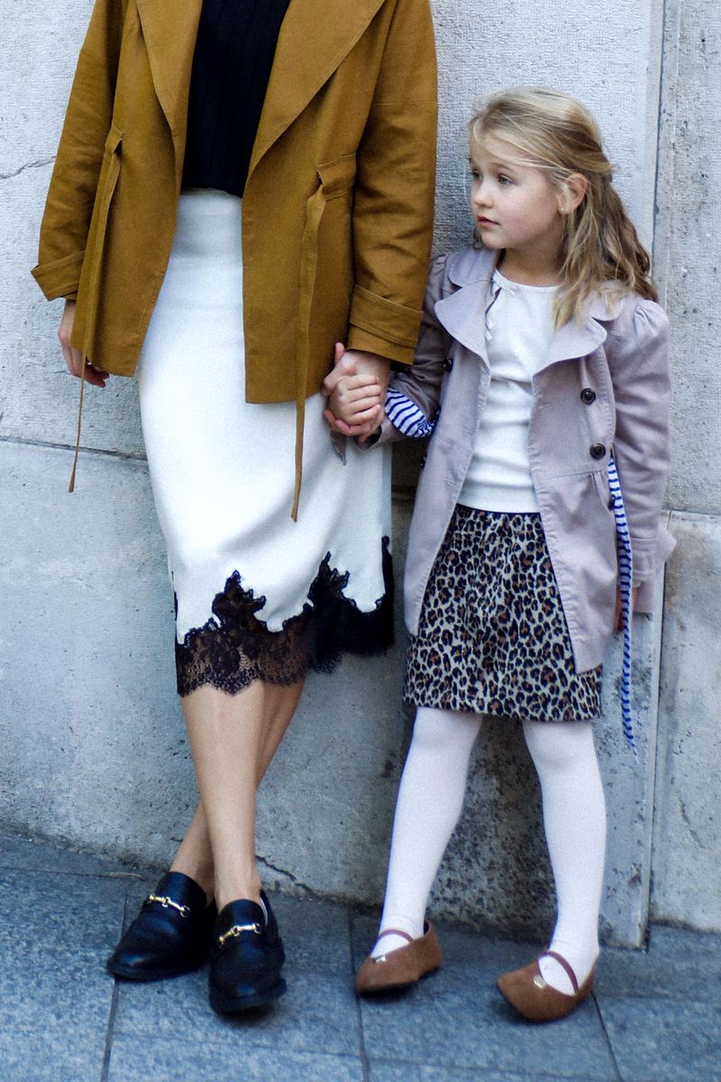 Mother and daughter holding hands against a stone wall
