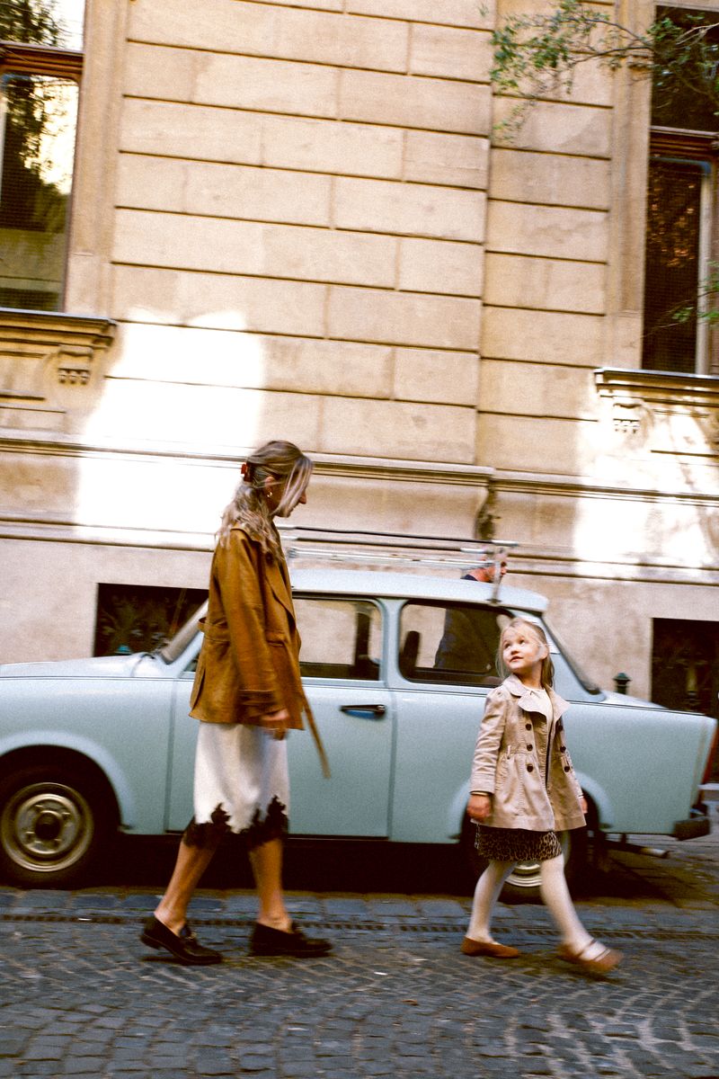 Mother and daughter walking past a pale blue vintage car