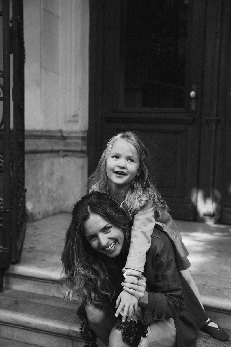Black and white: a girl climbs on her laughing mother's back on the steps