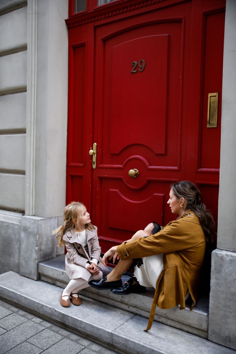 Mother and daughter talking on the steps of a red door