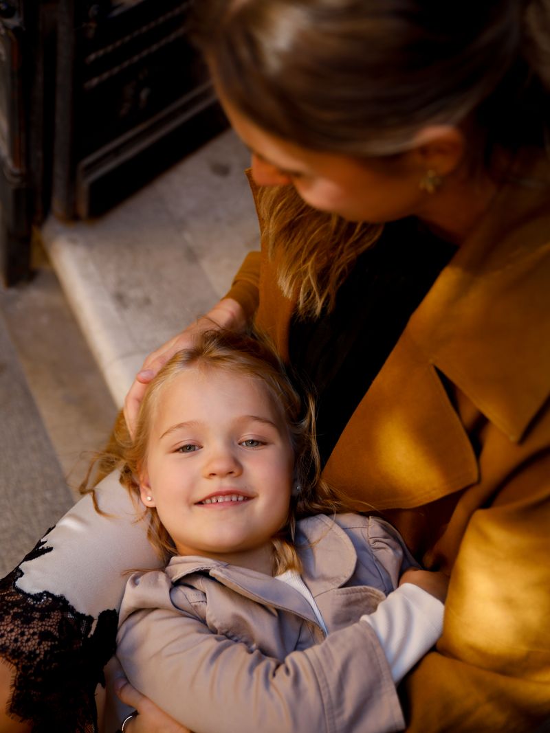 A smiling girl lying in her mother's lap in warm light